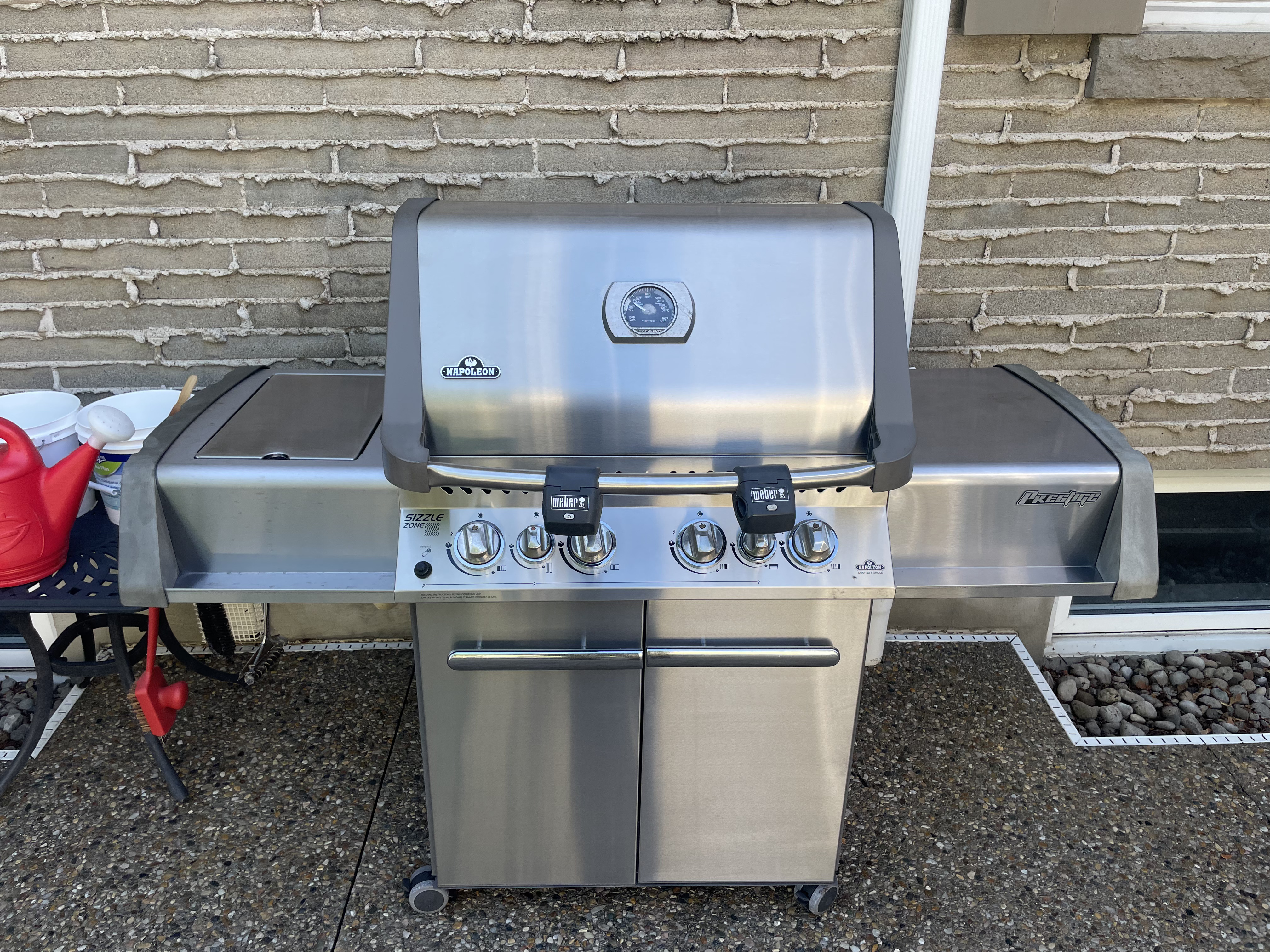 The same Napoleon Prestige after an Aspect deep clean, its stainless lid, control panel, side shelves and cart doors polished and streak-free