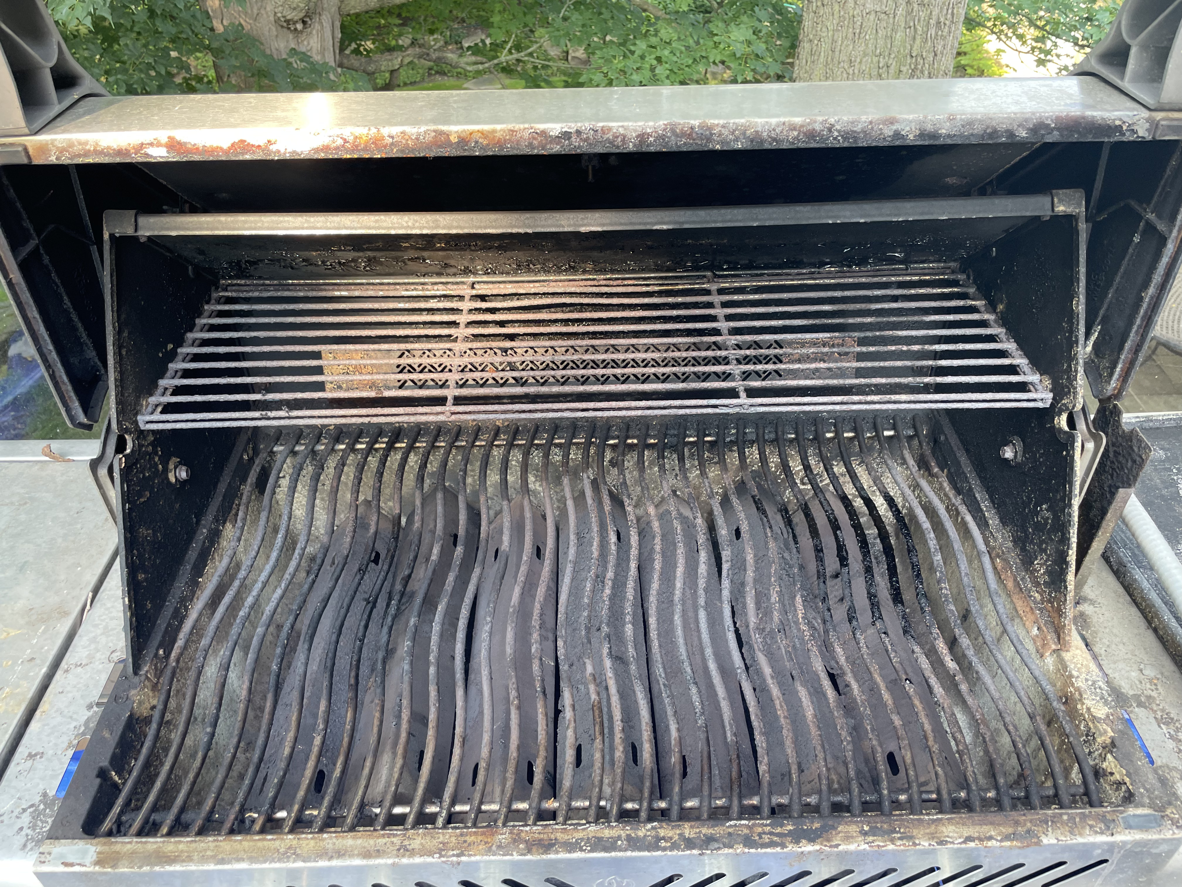 Inside that second Napoleon Prestige before an Aspect deep clean, with grease-crusted wavy grates, a blackened warming rack and grime along the firebox rim