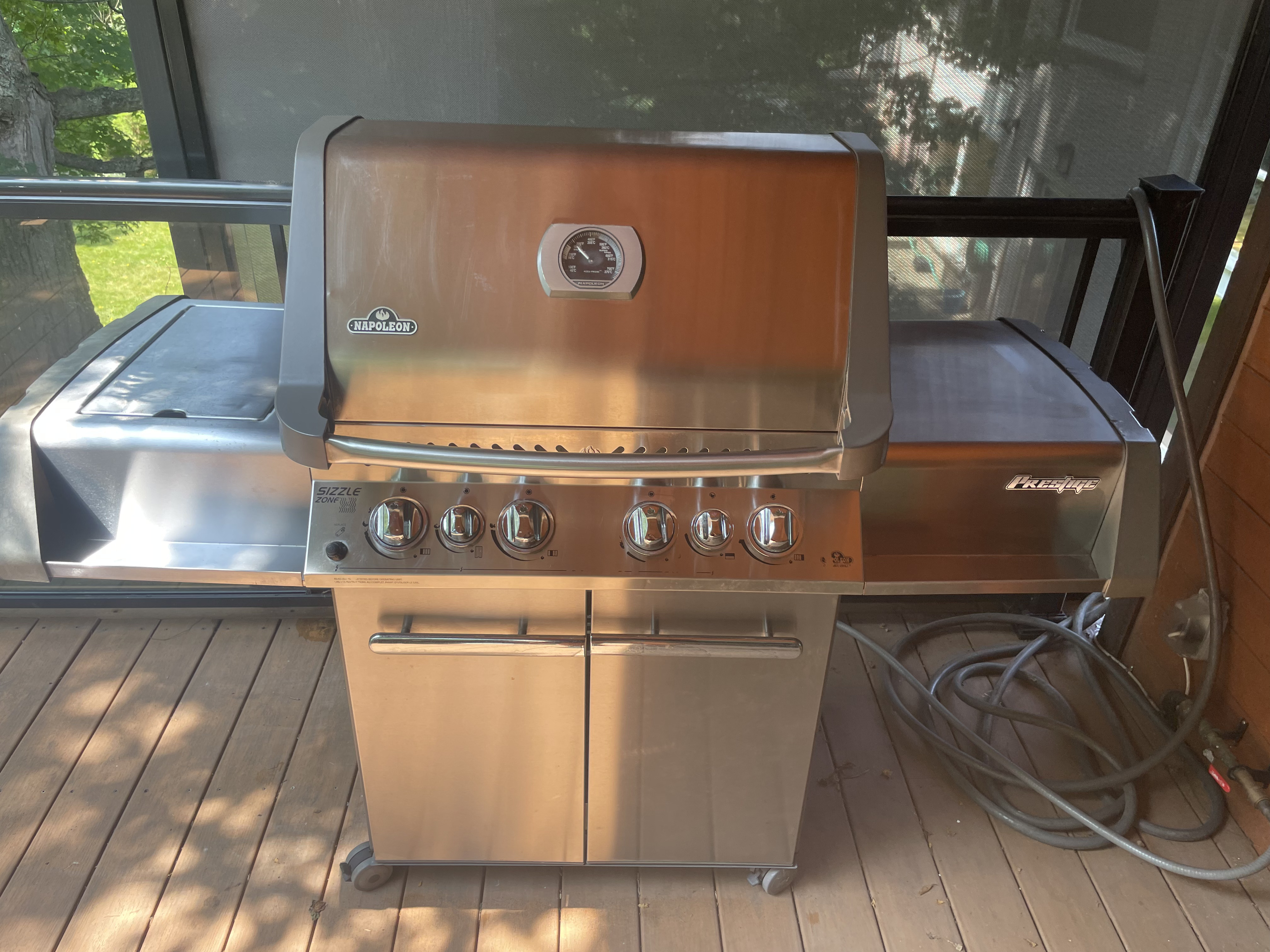 A second Napoleon Prestige back on its deck after an Aspect deep clean, lid, control knobs, side shelves and cart wiped clear of grease