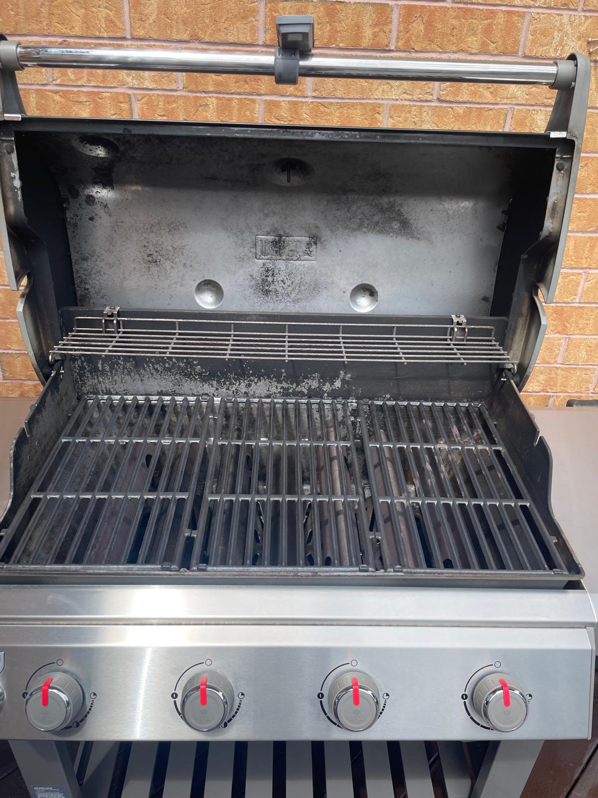 Inside the same four-burner Weber Genesis after an Aspect deep clean, cooking grates and warming rack stripped back to bare metal