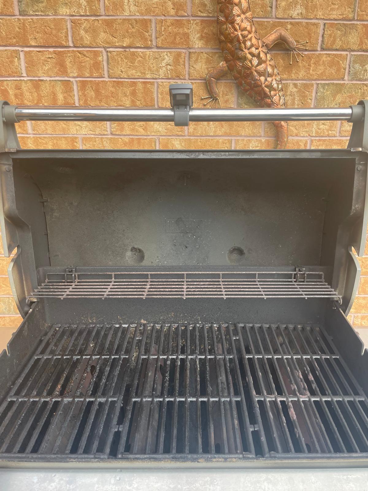 Inside a four-burner Weber Genesis before an Aspect deep clean, with grease-blackened cooking grates and a carbon-caked lid and warming rack